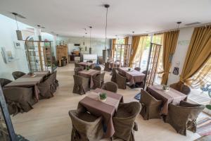 a restaurant with tables and chairs in a room at Alpen Hotel Eghel in Folgaria