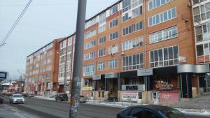 a tall brick building on a city street with cars at OK! Розы Люксембург in Tomsk