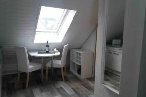 una pequeña cocina con mesa, sillas y ventana en Helle 2-Zimmerwohnung am Stadtrand, en Hildesheim