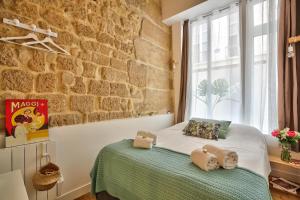 Cama en habitación con pared de ladrillo en New Stunning 4 Bdrs Apt, With AC – Le Marais, en París