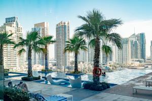 a pool with palm trees and a city in the background at HiGuests - Unique Studio With Stunning Panoramic Marina Views in Dubai