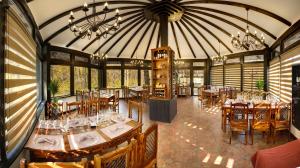 a dining room with tables and chairs and a chandelier at Hotel Cornul Vanatorului in Piteşti