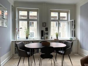 - une salle à manger avec une table, des chaises et des fenêtres dans l'établissement ApartmentInCopenhagen Apartment 308, à Copenhague