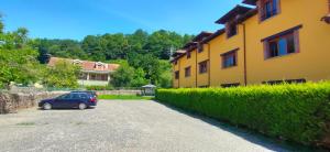 a car parked in a parking lot next to a yellow building at Apartamentos El Castañeu in Corao