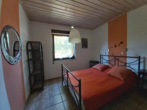ein Schlafzimmer mit einem Bett mit einer orangefarbenen Decke und einem Spiegel in der Unterkunft Domek pod Pobierowem in Gostyniec