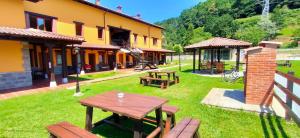 a yard with picnic tables and a building at Apartamentos El Castañeu in Corao