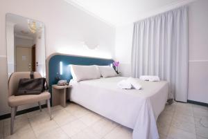 a bedroom with a large white bed and a chair at Hotel Grifo in Rome