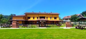 a large yellow building with picnic tables in a park at Apartamentos El Castañeu in Corao