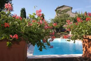 a swimming pool with red flowers in front of a house at Alloggio Castello di Loreto in Todi