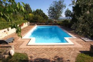 a large swimming pool in a yard with a brick patio at Alloggio Castello di Loreto in Todi