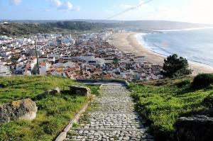 un camino de piedra que conduce a una playa con casas en Casa Avó Rosa, en Nazaré