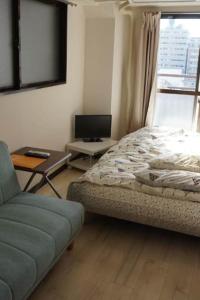 sypialnia z łóżkiem, stołem i kanapą w obiekcie CUBIC.30 w mieście Hiroszima