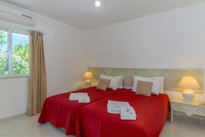 um quarto com uma cama vermelha com duas toalhas em FLH Balaia Village Apartment with Pool I nos Olhos de Água