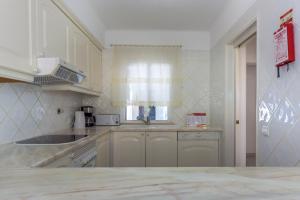 a kitchen with white cabinets and a sink and a window at FLH Balaia Village Apartment with Pool I in Olhos de Água