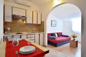 a kitchen and a living room with a red couch at Villa Senjkovic - Apartments with Balcony and Sea View in Bol