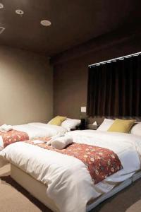 a bedroom with three beds with white sheets and a window at Sumiya Spa & Hotel in Hiroshima