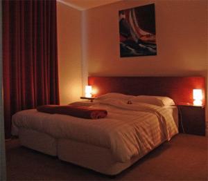 a bedroom with a large bed with two lamps at Hotel Mieke Pap in Poppel