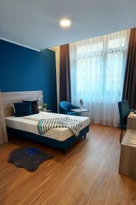 1 dormitorio con 1 cama grande y pared azul en New Work Hotel Essen en Essen