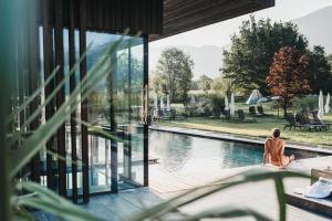 a woman sitting on a porch next to a swimming pool at Hotel Rudolf in Brunico
