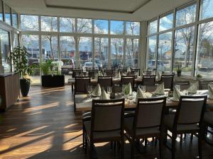 a dining room with tables and chairs and windows at Hotel Asgard in Gersthofen