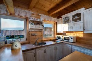 a kitchen with white cabinets and a sink and two windows at Arctic House in Dolný Kubín