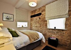 a bedroom with a brick wall and a bed at Thornton in Chipping Campden