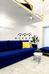 OUCHI HOTEL Higashi-Hiratsuka #302 في هيروشيما: غرفة معيشة مع أريكة زرقاء وطاولة