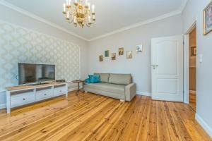 a living room with a couch and a flat screen tv at Victus Apartamenty, Apartament Dębowa in Sopot