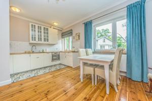 a kitchen with a table and chairs and a large window at Victus Apartamenty, Apartament Dębowa in Sopot