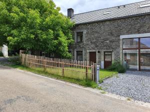 ein Backsteinhaus mit einem Holzzaun an einer Straße in der Unterkunft Maison Demar in Gedinne