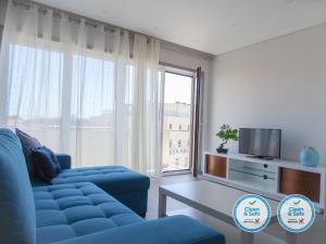 a living room with a blue couch and a large window at RS Porto Apartments in Porto
