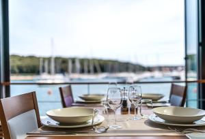 a table with glasses and plates and a view of the water at Ribarska Koliba Resort in Pula