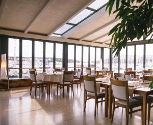 a dining room with tables and chairs and windows at Ribarska Koliba Resort in Pula