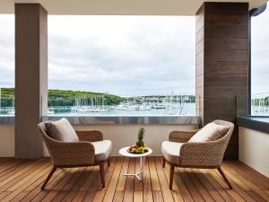 a balcony with two chairs and a table with a view of a harbor at Ribarska Koliba Resort in Pula