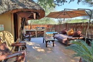 a patio with a couch and an umbrella at Manzini Chalets in Marloth Park