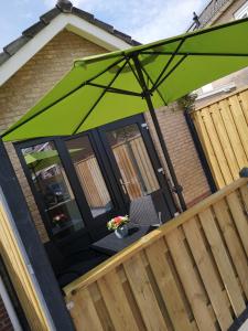 a green umbrella sitting on a wooden deck at Studio Zwin 9 in Zoutelande