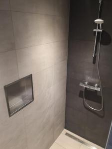 Un baño con ducha con puerta de cristal. en Studio Zwin 9, en Zoutelande