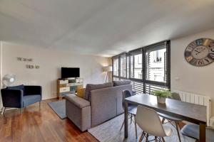 a living room with a couch and a table and a clock at LE SAINT-MICHEL - Appartement Cosy in Bordeaux