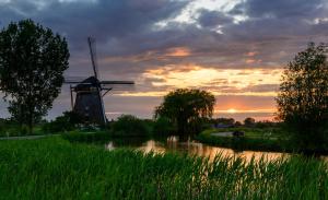 a windmill and a river with a sunset in the background at Mondriaanmolen, a real Windmill close to Amsterdam in Abcoude +8 photos