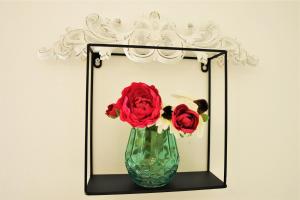 a vase with red roses in front of a mirror at Iva Apartmani in Vodice