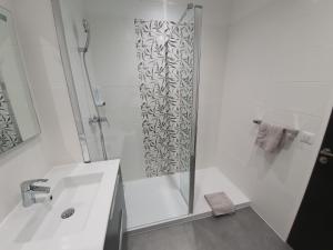 uma casa de banho branca com um chuveiro e um lavatório. em L'épopée Panoramique - Parking - Avenue de Champagne - Epernay em Épernay