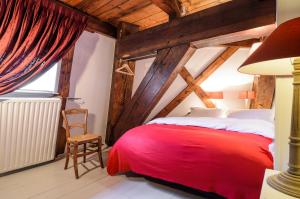 1 dormitorio con 1 cama roja y 1 silla en Mondriaanmolen, a real Windmill close to Amsterdam en Abcoude