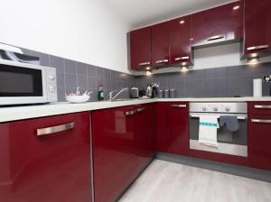 a kitchen with red cabinets and a microwave at Valdeni Apartments in Leeds