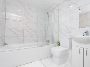 a white bathroom with a tub and a toilet and a sink at Valdeni Apartments in Leeds