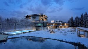 a building in the snow next to a pond at Bonfanti Design Hotel in Chienes