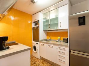 een keuken met witte kasten en een oranje muur bij Tapioles · Lovely apartment Tapioles in Barcelona +22 foto's