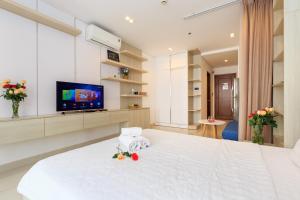 1 dormitorio con 1 cama blanca grande y TV de pantalla plana en Sky homes Block A, en Ho Chi Minh