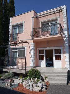 a pink house with stairs and a balcony at Atlas Apartman in Bük