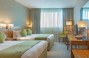 a hotel room with two beds and a desk at CityNorth Hotel & Conference Centre in Gormanston