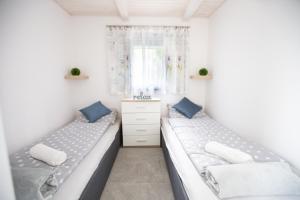 two beds in a room with white walls and blue pillows at Silver House vendégház in Orosháza